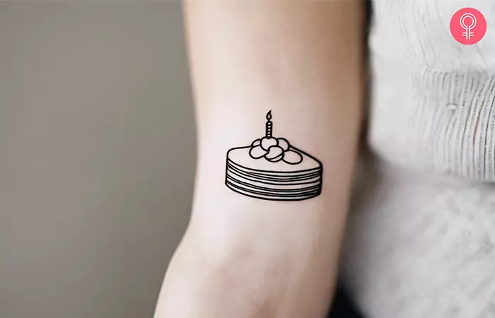 Minimalist cake tattoo on the upper arm