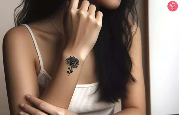 A minimalist chrysanthemum tattoo on a woman’s forearm