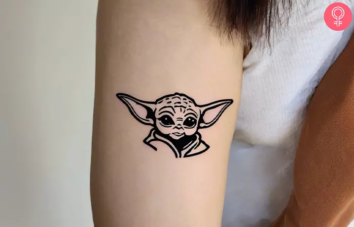 Minimalist Yoda tattoo on the inner arm