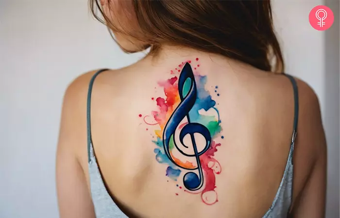 A woman with a paintbrush treble clef tattoo on her back