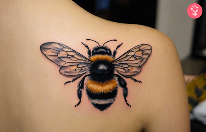 A realistic bumble bee tattoo on the back of the shoulder