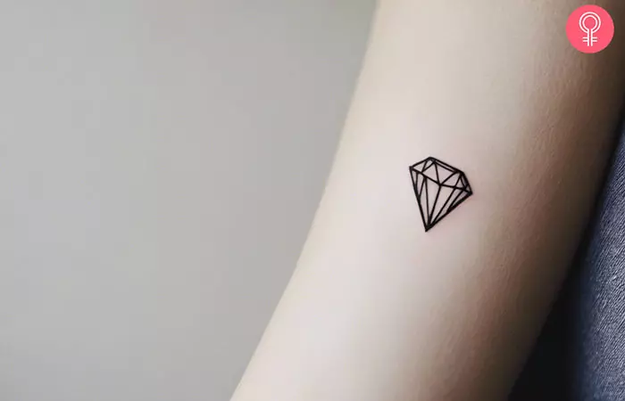 A woman with a small diamond tattoo on her arm