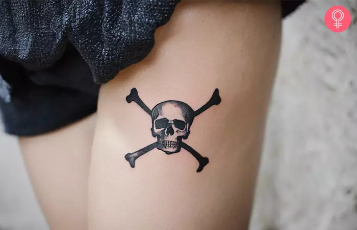A woman with a small skull and crossbones tattoo on her thigh