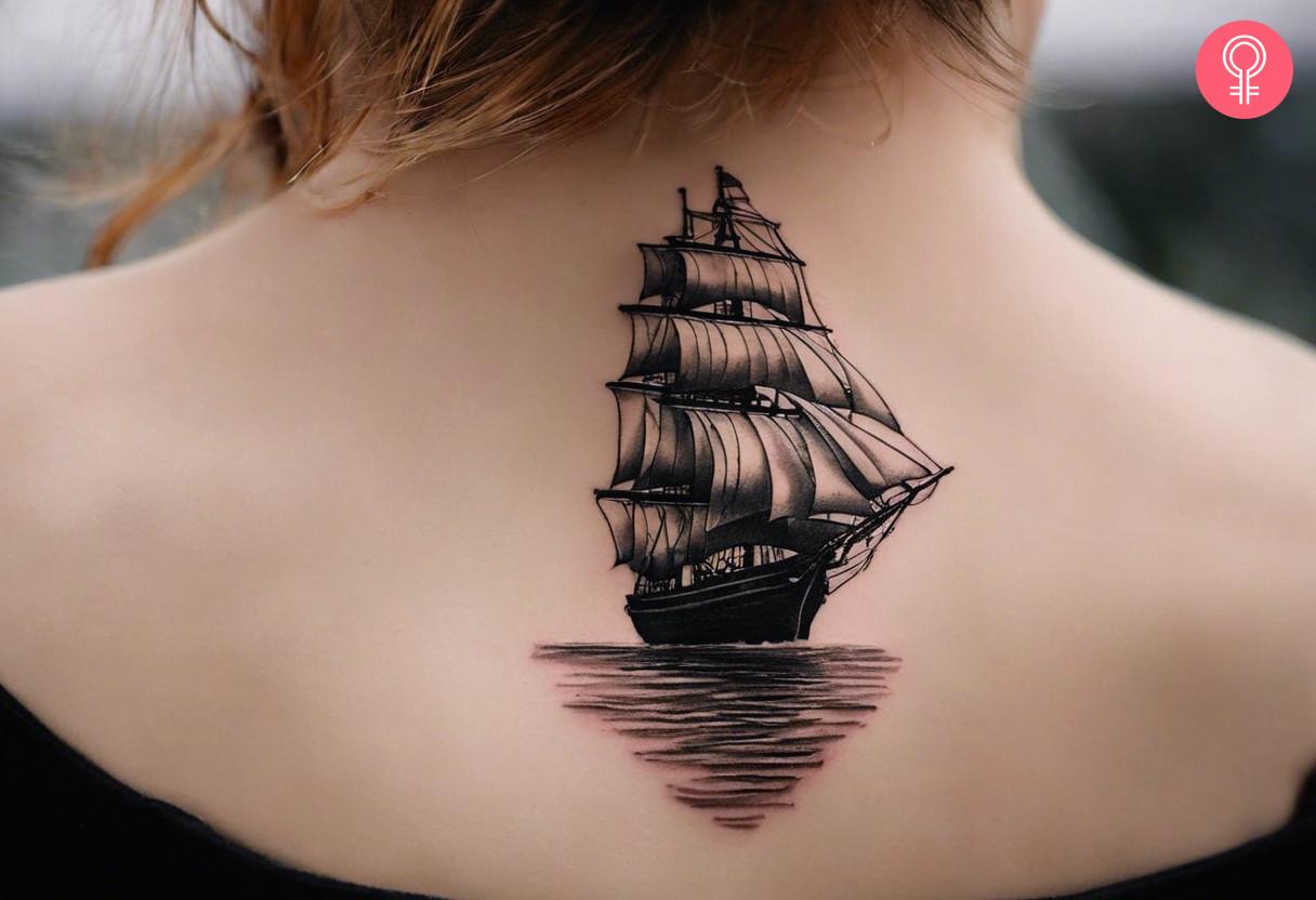 Small realistic ship tattoo on a woman's upper back