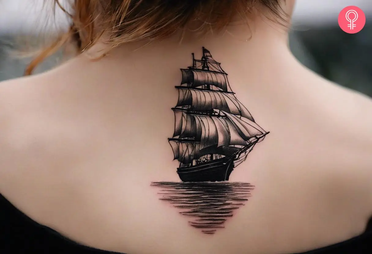 Small realistic ship tattoo on the upper back of a woman