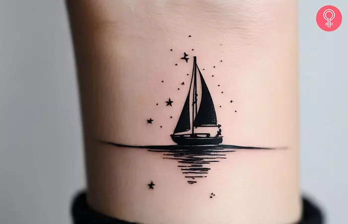 Woman with stars at night sailboat tattoo on her wrist