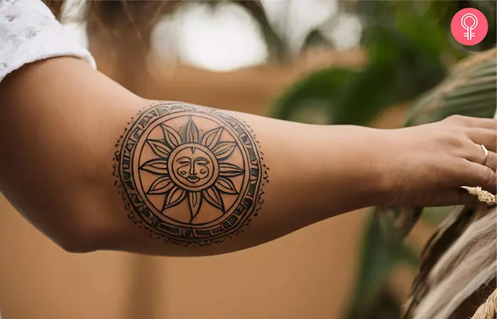 A woman with a Taino sun tattoo on her forearm