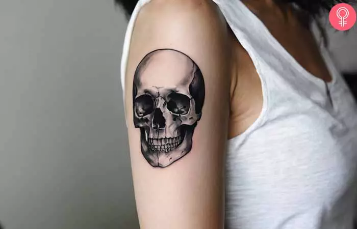 A woman with a blackwork skull tattoo design on her upper arm