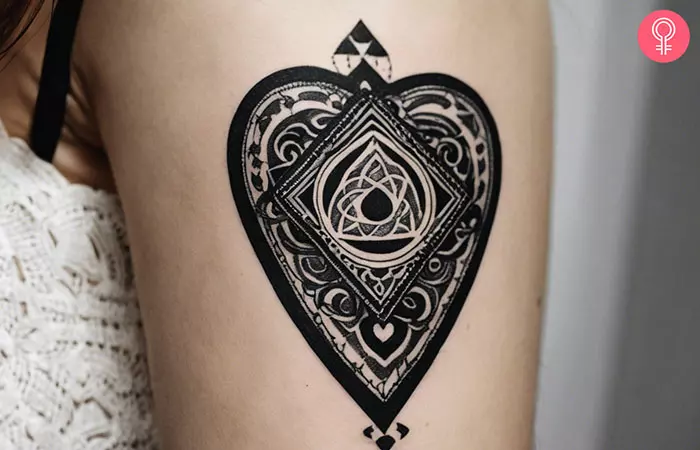 A monochromatic planchette tattoo on a woman’s upper arm