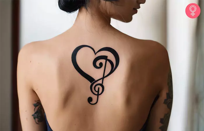 Woman with a treble clef and bass clef heart tattoo on her back