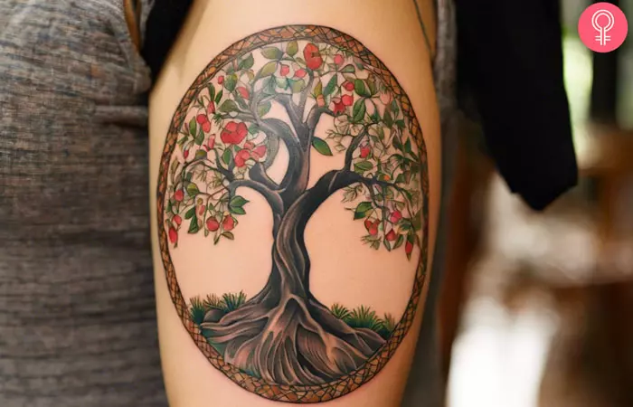 A woman sporting a tree of life and death tattoo on her upper arm