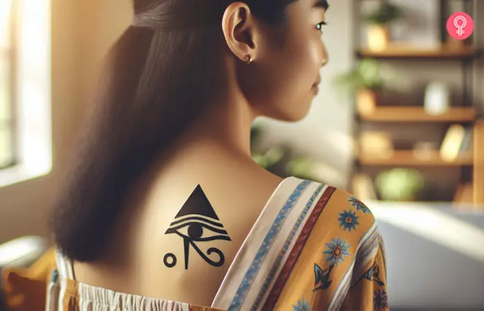 A triangle eye of Horus tattoo on the upper back
