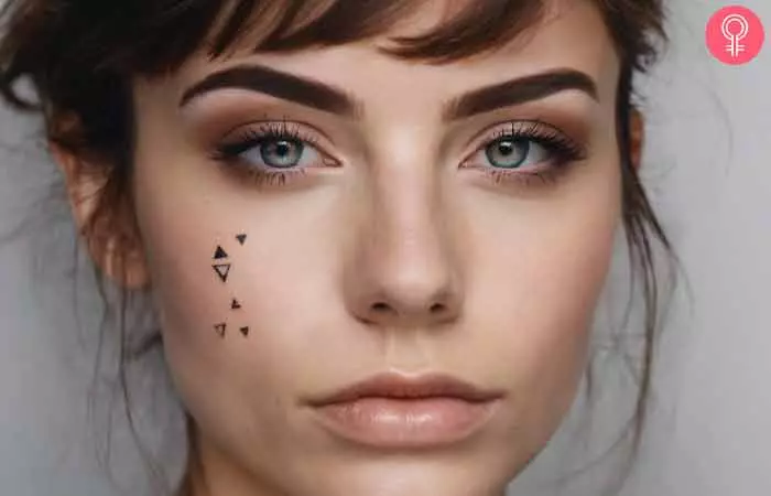 A cluster of triangles tattooed under the eye