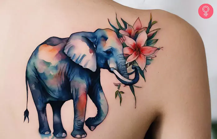 A blue watercolor elephant with flowers on a woman’s back