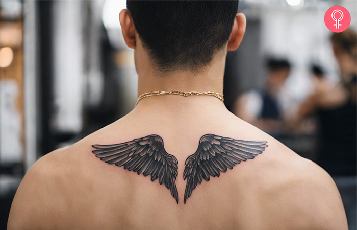 A man with wings tattoo design on upper back 