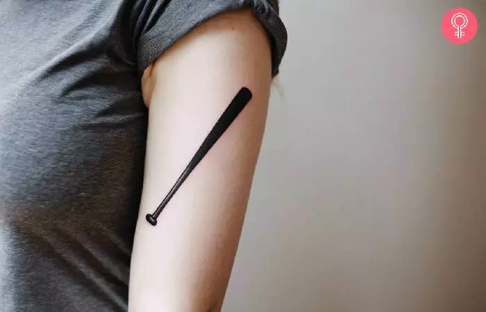 Woman with a baseball bat tattoo on the upper arm