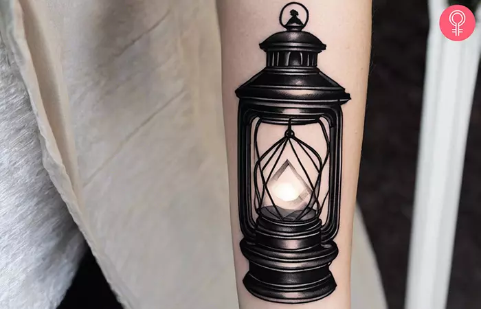 Woman with a black lantern tattoo on the forearm