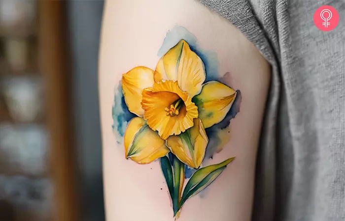A yellow daffodil tattoo on the upper arm