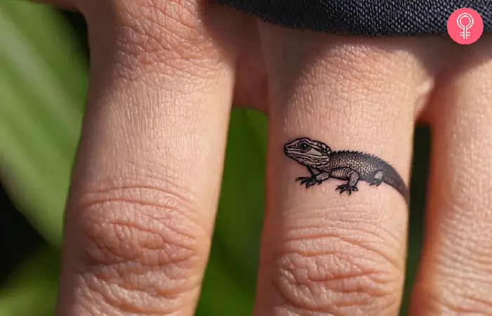 woman with a small bearded dragon tattoo on his finger