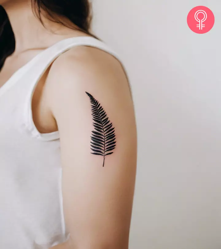 A simple fern tattoo on the arm of a woman