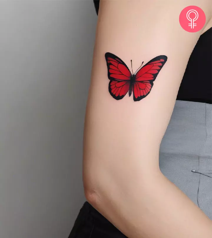 A woman with a red butterfly tattoo on her upper arm