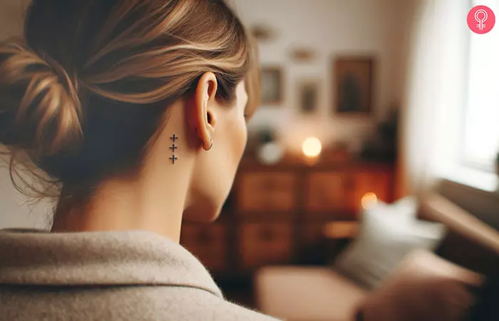 A 3-cross tattoo behind a woman's ear