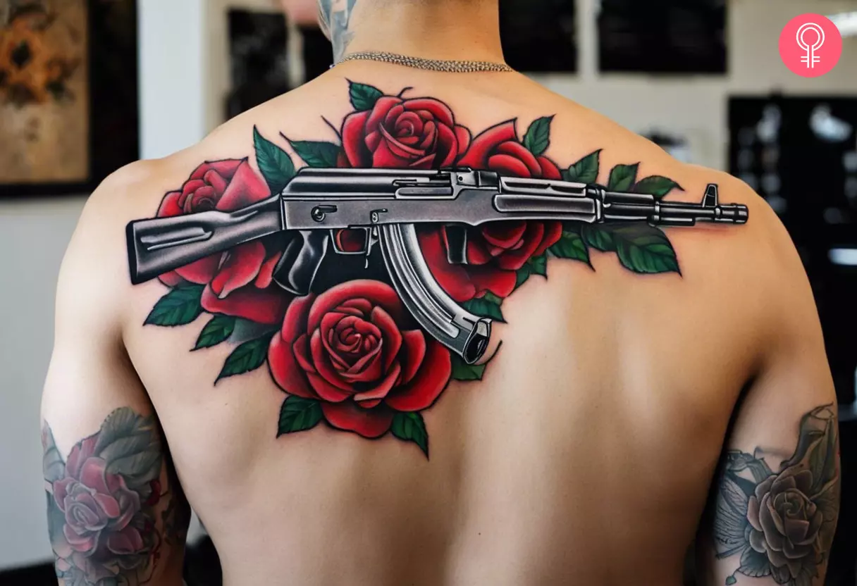 A back tattoo of an AK-47 on a bed of roses