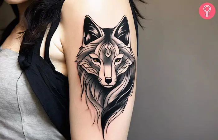 A black and white kitsune tattoo on a woman’s upper arm
