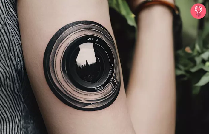 A camera lens tattoo on the arm