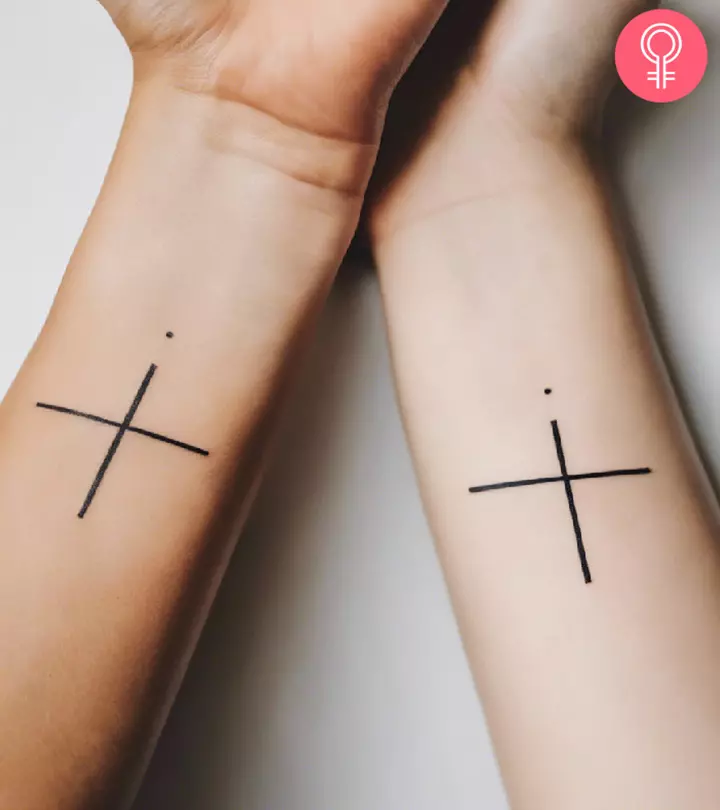A cross tattoo on the wrists of two sisters