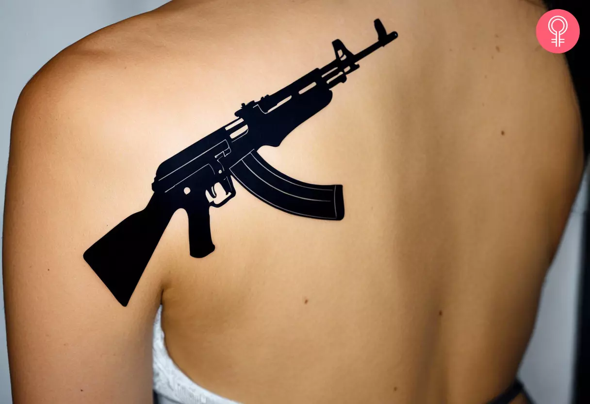 A large AK-47 silhouette tattoo on a woman’s back