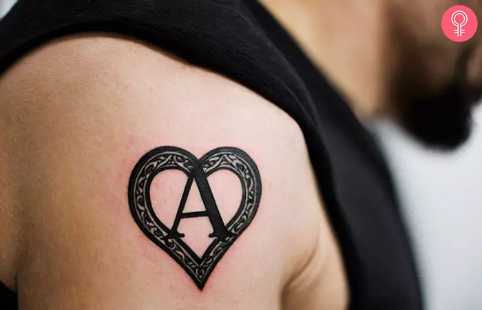 A letter A tattoo with a heart on a man’s upper arm