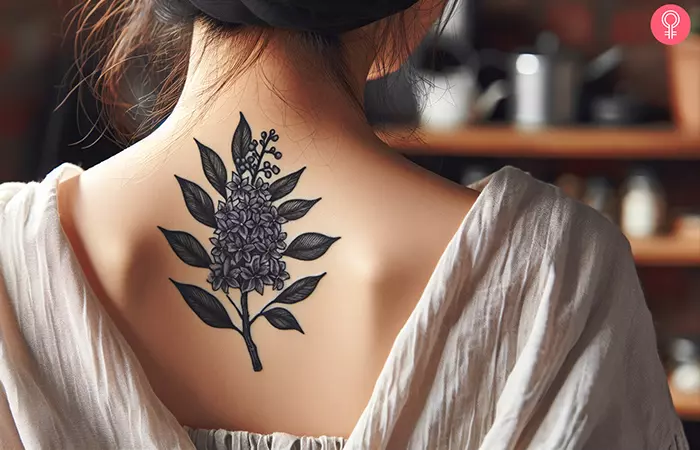 A lilac branch tattoo on the upper back