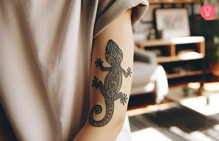 A mandala lizard tattoo on the arm of a woman