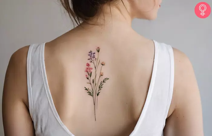 A minimalist wildflower tattoo on the upper back