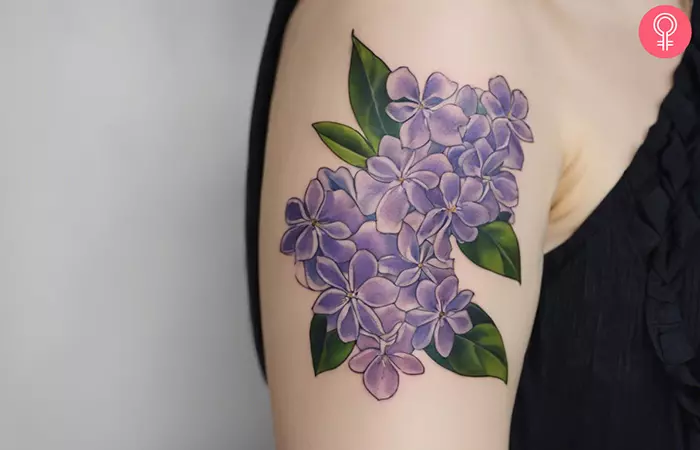 A purple lilac tattoo on the upper arm
