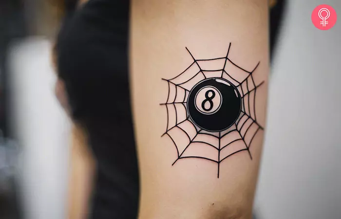 A spiderweb and 8 ball tattoo on the arm