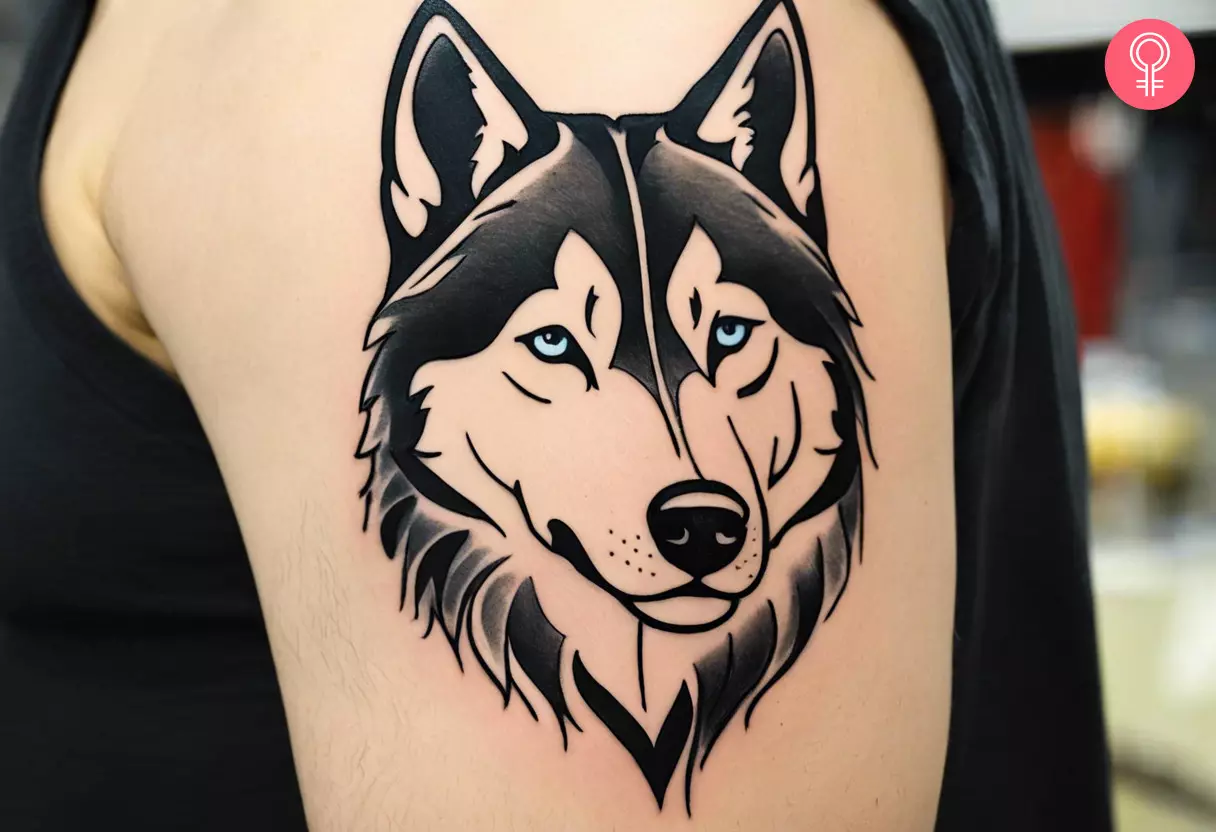 A tattoo on the arm of a man featuring a blue-eyed husky