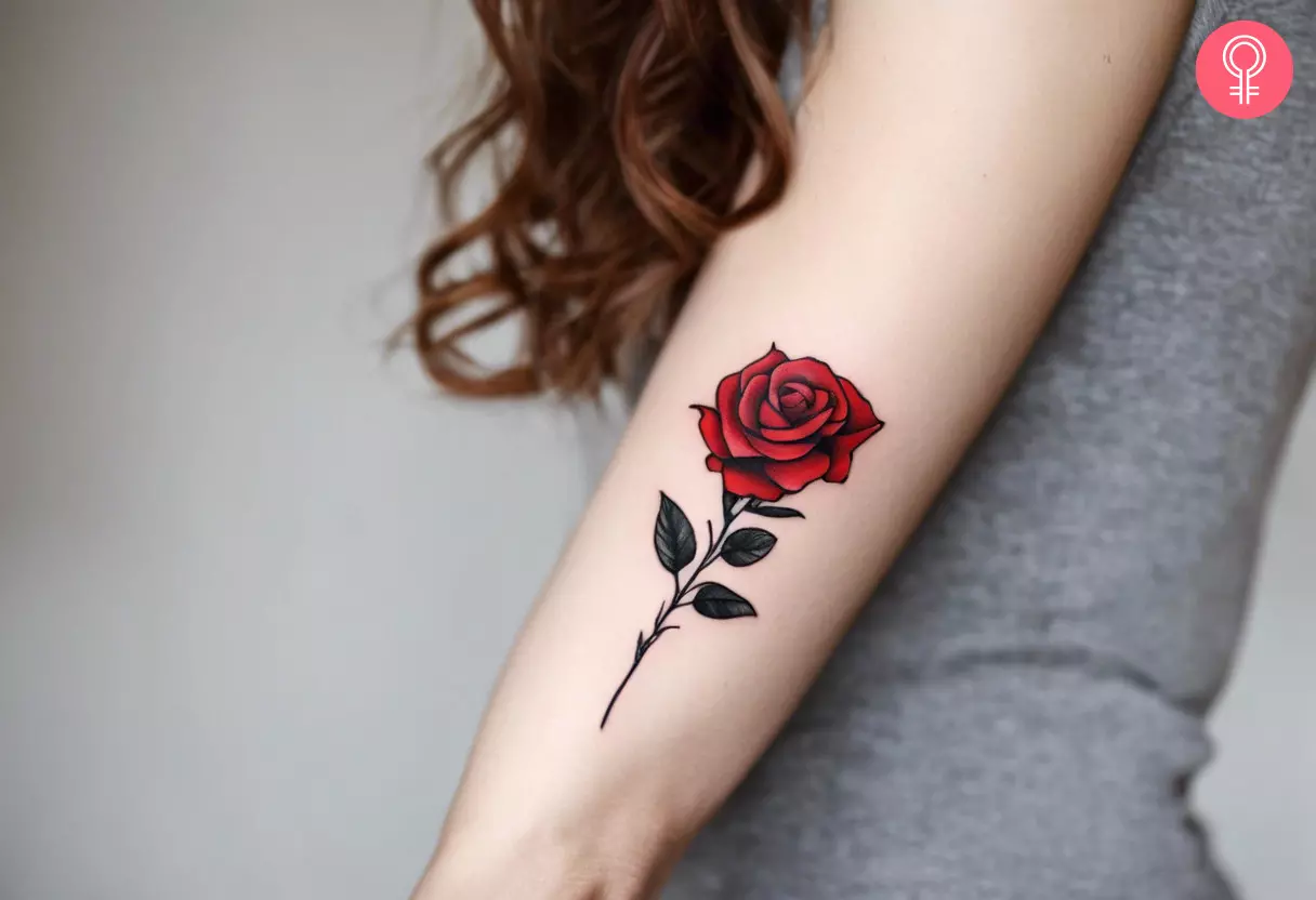 A woman flaunting a realistic red rose tattoo with a stem on the upper arm