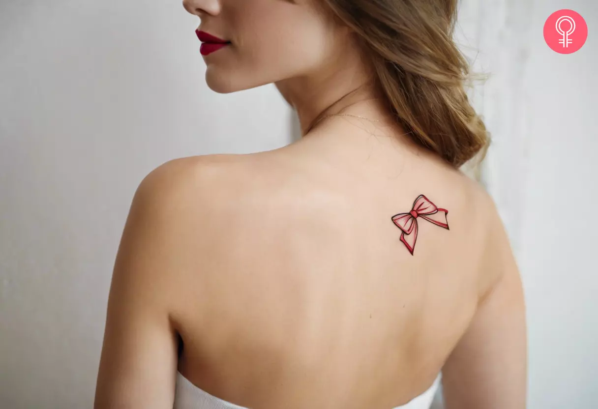 A woman flaunting a wispy coquette red bow tattoo on the back