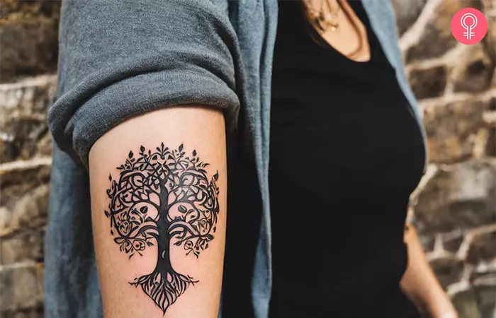 A woman with a fine-line Yggdrasil tattoo on her arm