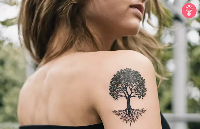 A woman with a minimalist Yggdrasil tattoo on her upper arm