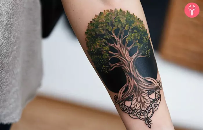 A woman with a realistic Yggdrasil tattoo on her forearm