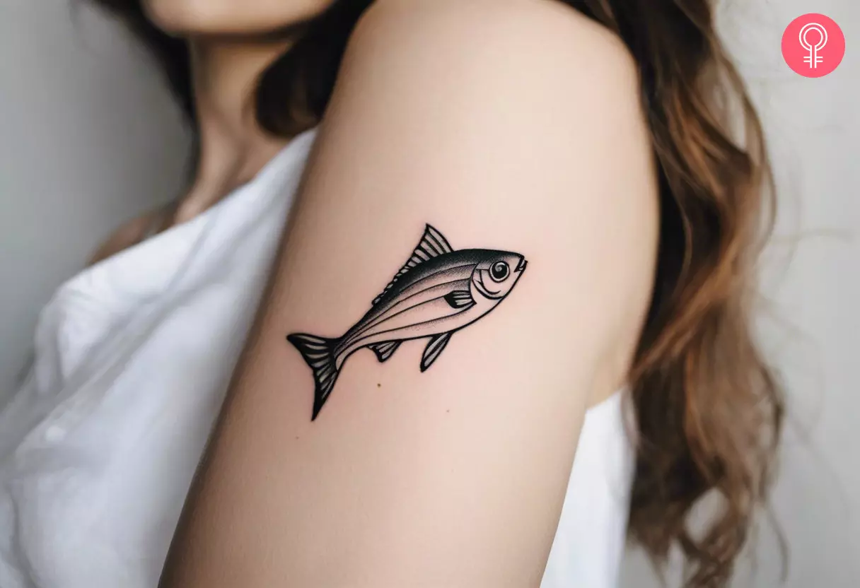 A woman with a small fish tattoo on her upper arm