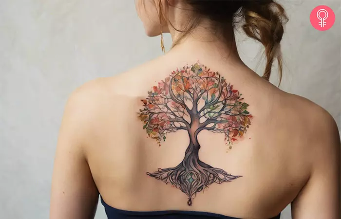 A woman with a watercolor Yggdrasil tattoo on her back