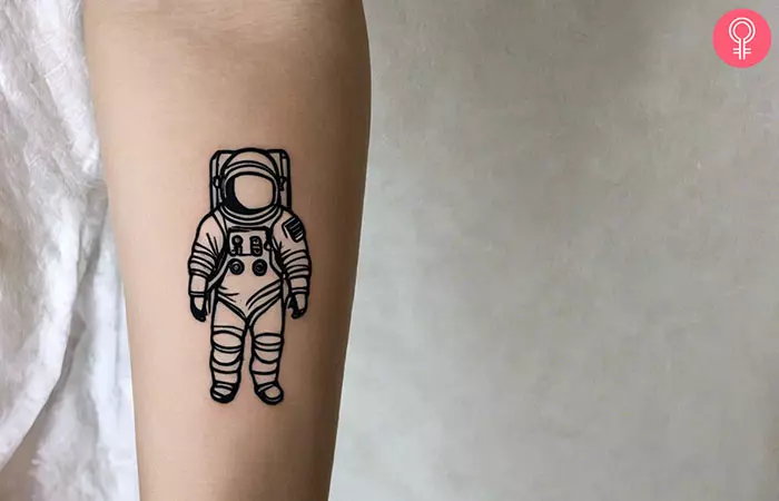 An astronaut tattoo outline on a woman’s forearm