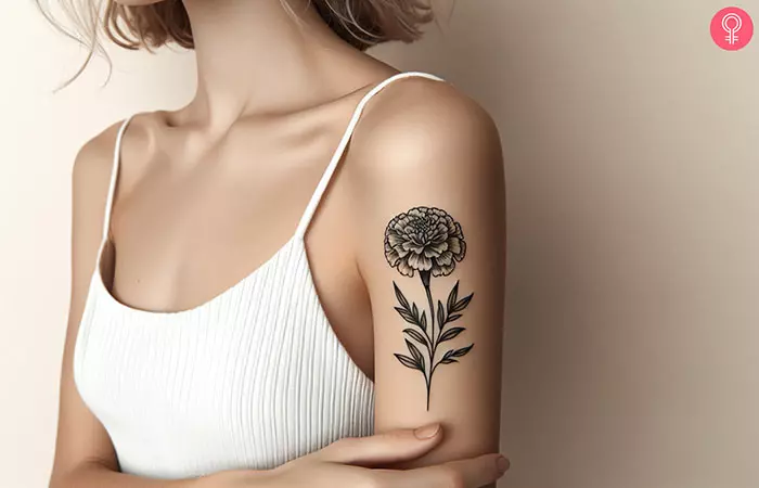 A black and white marigold tattoo on the upper arm