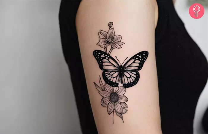 A black monarch butterfly tattoo on a woman’s upper arm