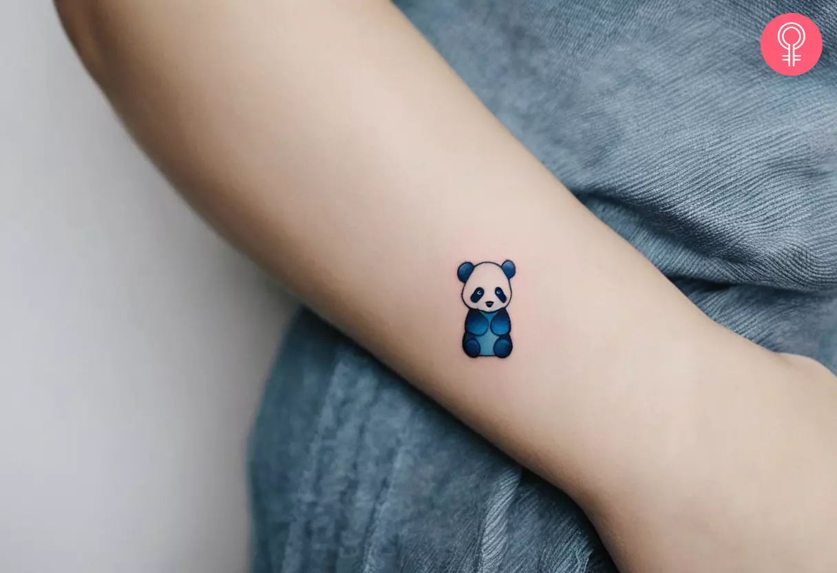 A blue panda tattoo design on a woman’s lower arm