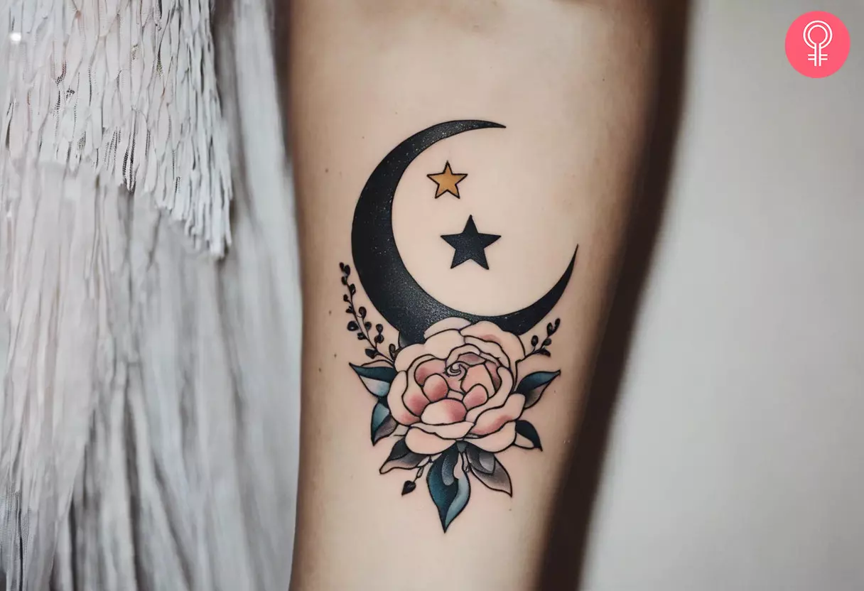 A tattoo of a crescent moon and stars on the forearm